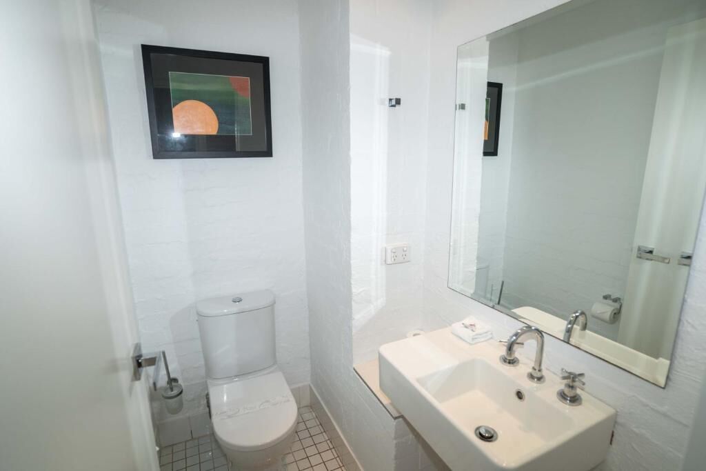 A small, modern bathroom with a toilet, sink, and mirror.