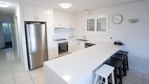 A modern kitchen with white cabinetry, stainless steel appliances, and a large island with bar stools.