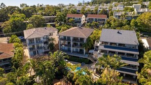 A residential area with multiple two-story houses, a swimming pool, and lush greenery.