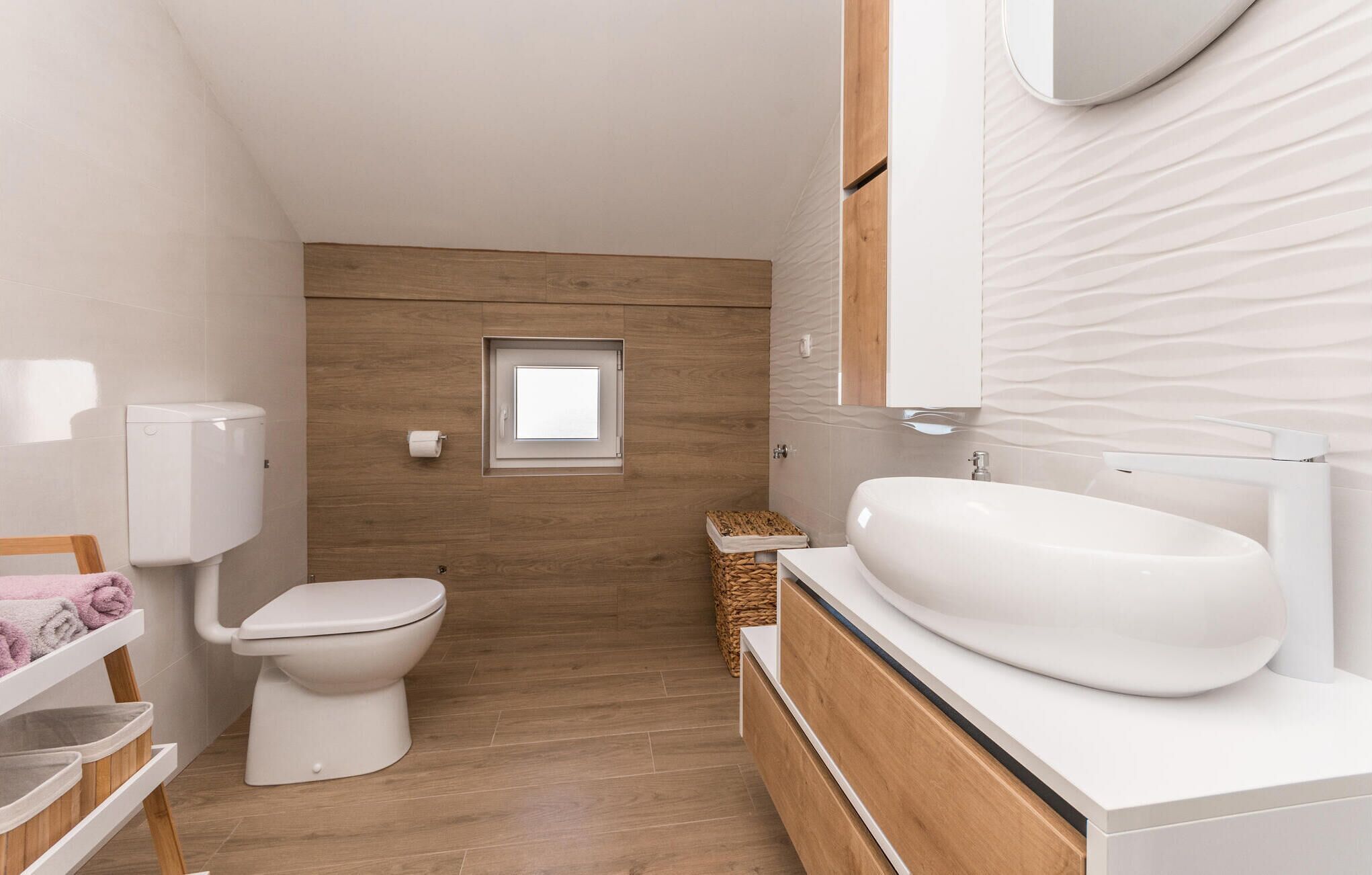 A modern bathroom with a toilet, a sink, and a small window.