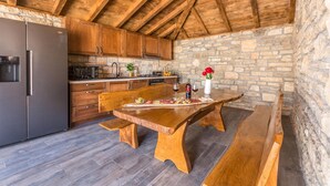 Una cucina rustica con mobili in legno, un muro in pietra e un tavolo da pranzo in legno apparecchiato per un pasto.
