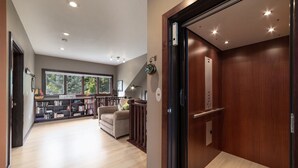 A spacious living area with a large bookshelf, a sofa, and a wooden door leading to an elevator.