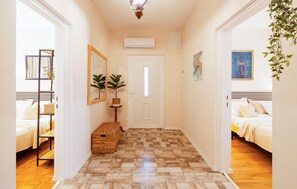 A hallway with a wooden herringbone floor, a white door, and a bed with a white headboard on the right. - Lovely home in Seline (Seline)
