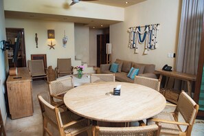 A spacious living area with a round wooden table, wicker chairs, a sofa with blue cushions, and a wall-mounted decorative rope. - Penthouse - Jacuzzi - BEACH CLUB -Heated Pool, Jacuzzi, Spa, Gym  7 (Playa del Carmen)