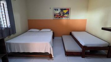 A room with two beds, a ceiling light, and a painting on the wall.
