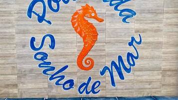 A wooden wall with the text "Pousada Sonho de Mar" and an orange seahorse.