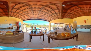 A spacious indoor area with a curved ceiling, a counter with food items, and a seating area with tables and chairs. - POUSADA SONHO DE MAR (Luis Correia)