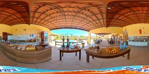 Un espacio interior amplio con techo curvo, una barra con productos alimenticios y una zona de estar con mesas y sillas.
