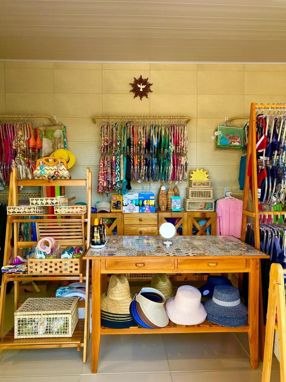 A room with a wooden desk, shelves with hats, and a wall decorated with a sun and hanging items.