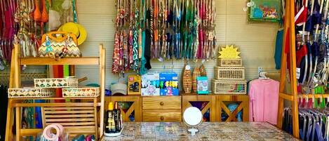 A room with a wooden desk, shelves with hats, and a wall decorated with a sun and hanging items.