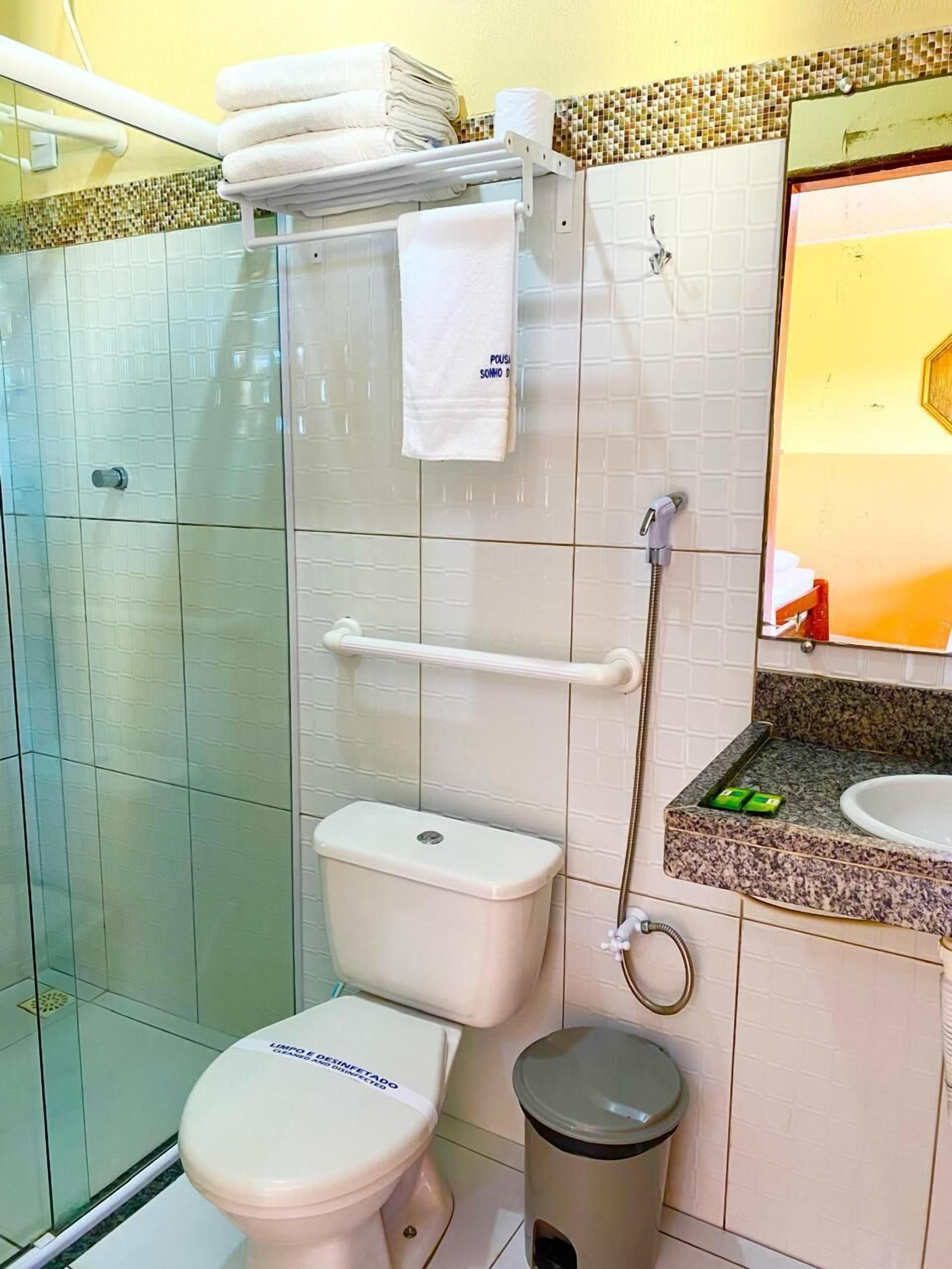 Un baño con inodoro, ducha, lavabo y un cubo de basura.