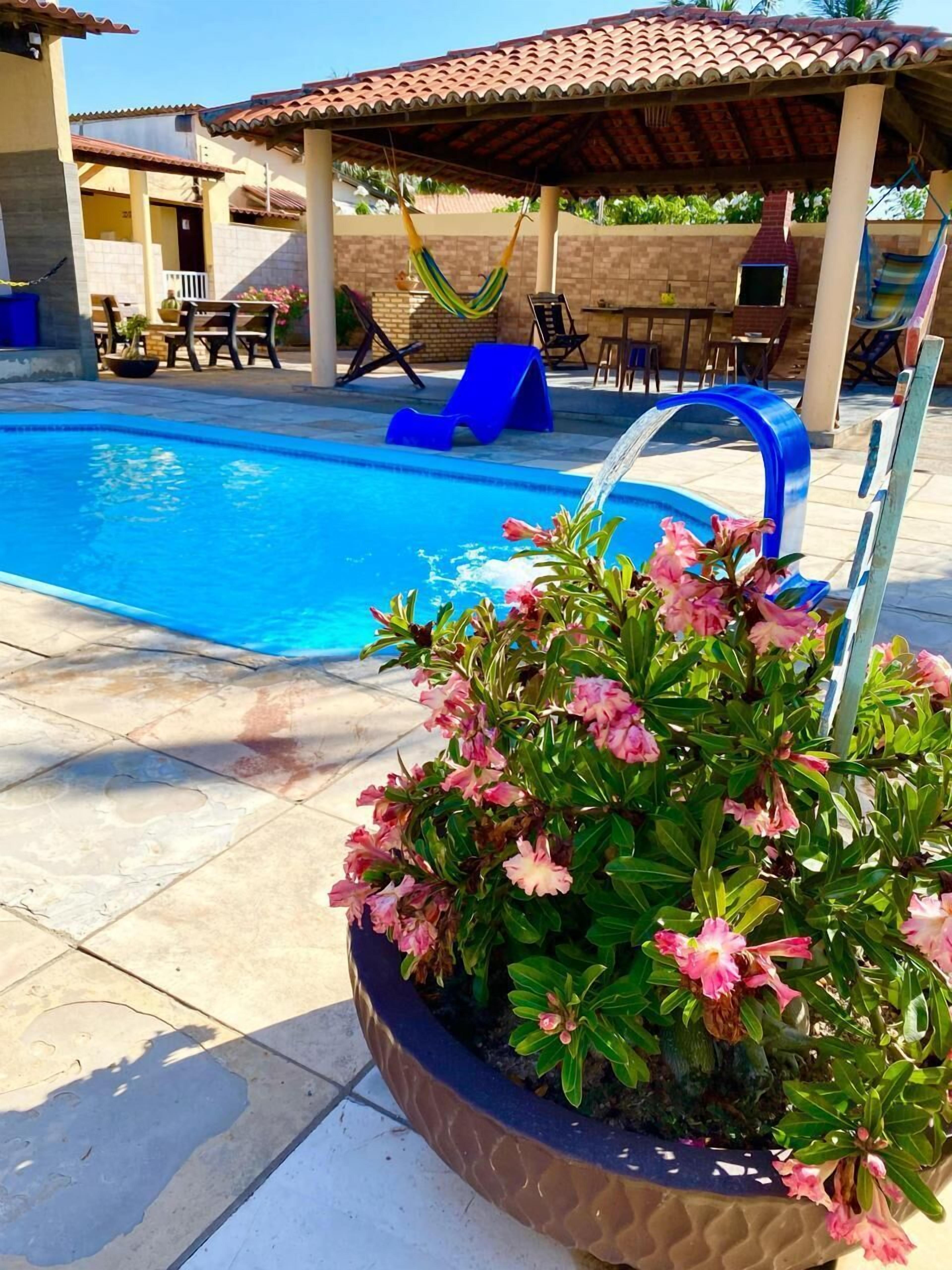 Una piscina con elemento d'acqua blu, circondata da sdraio e una zona patio coperta.