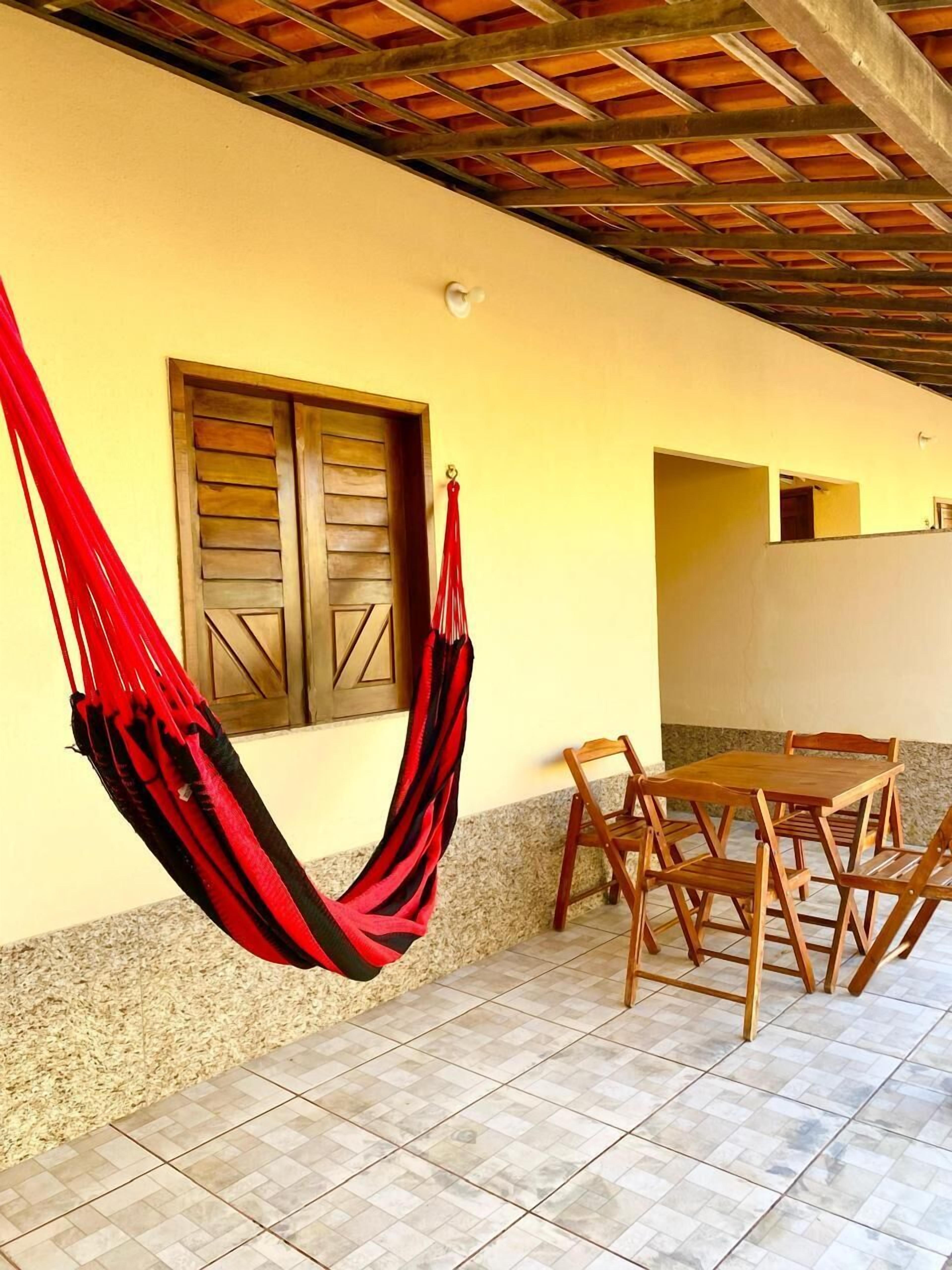 A hammock hanging on a wall, a wooden table with chairs, and a tiled floor.