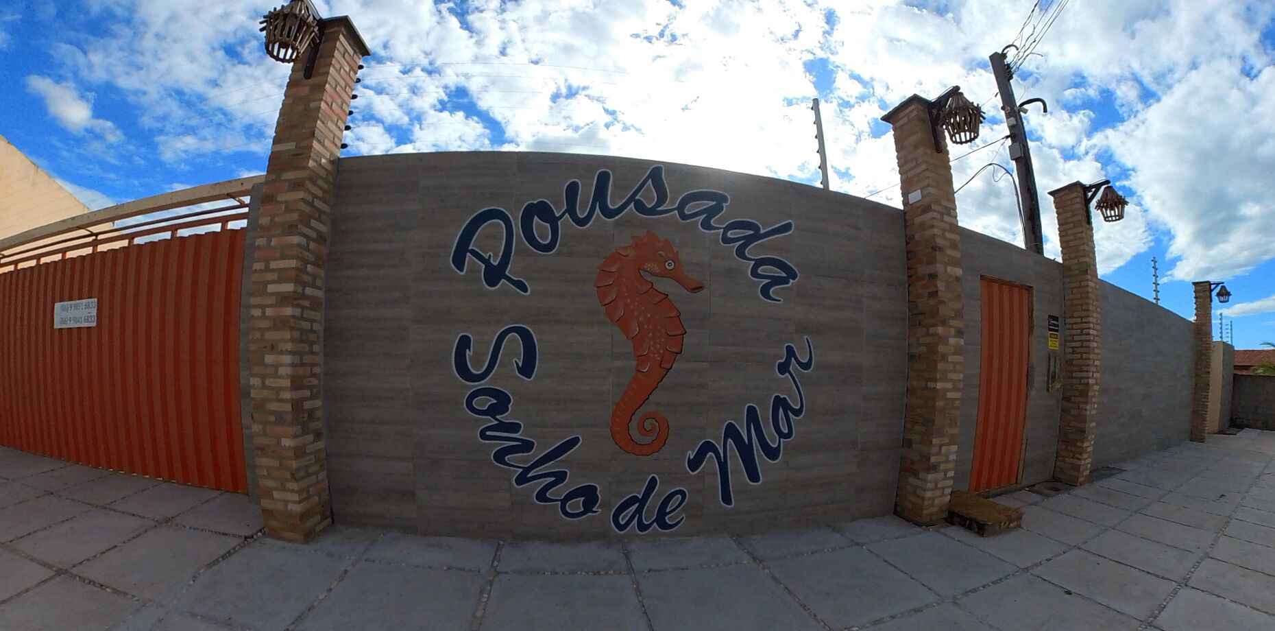 A building with a curved facade, featuring a large seahorse graphic and the text "Pousada Sonhos de Mar" in a stylized font.