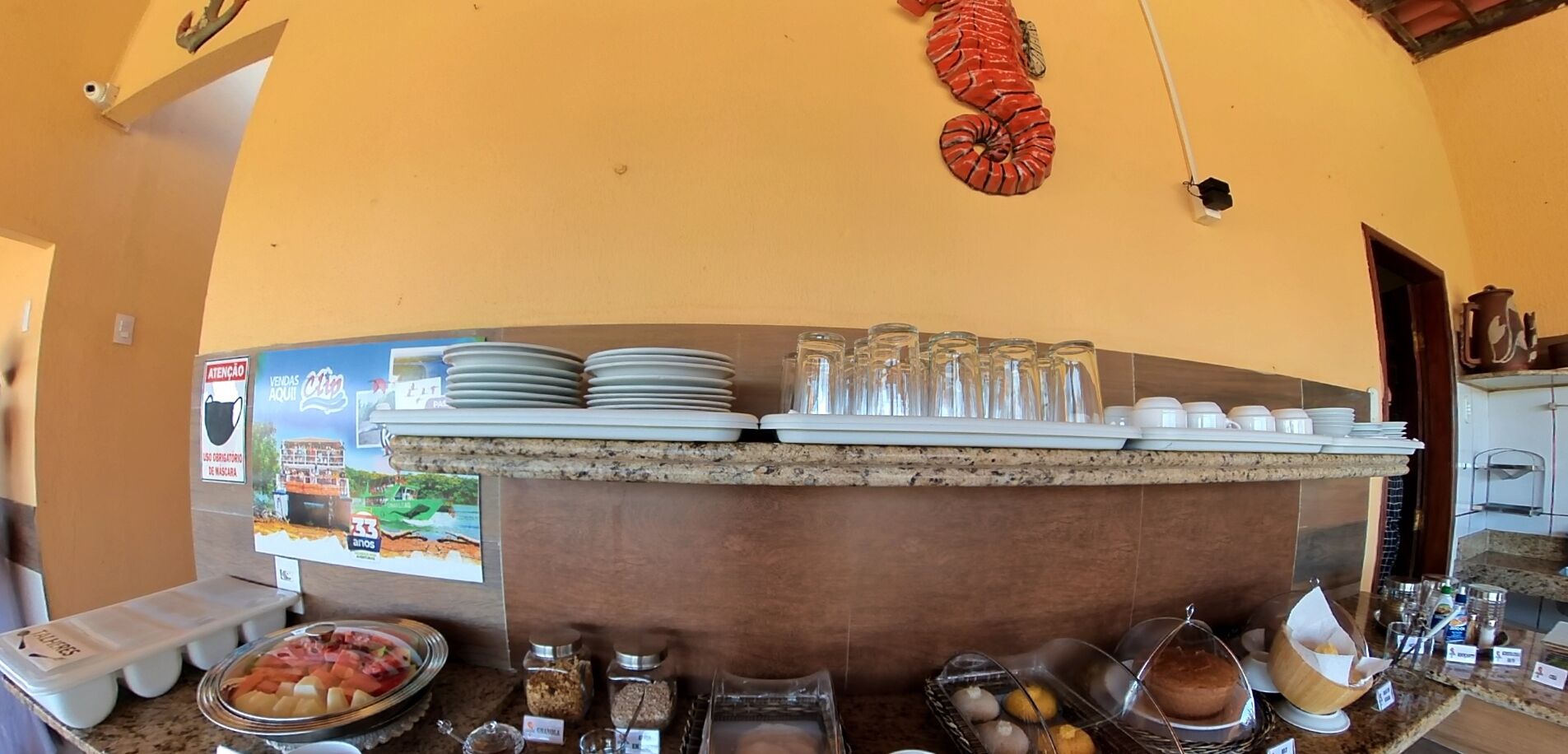 A buffet counter with plates, glasses, and various food items.