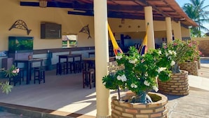 A covered outdoor seating area with brick planters, tables, and chairs. - POUSADA SONHO DE MAR (Luis Correia)