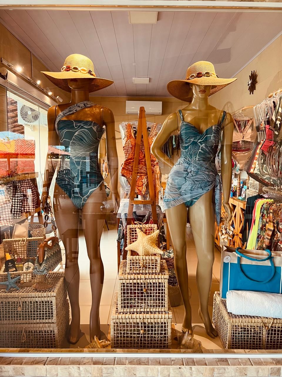 Mannequins in a store window displaying swimsuits and accessories.