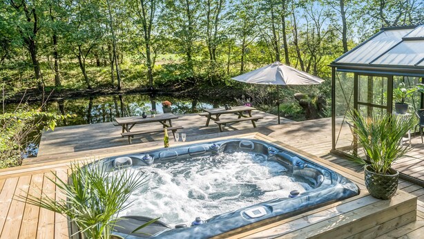 A wooden deck with a hot tub, picnic tables, and potted plants. - Amazing home in Grindsted with sauna (Grindsted)