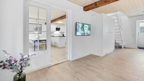 A modern interior with a wooden ceiling, a dining area with chairs and a table, a kitchen with white cabinets, and a TV mounted on the wall. - Amazing home in Grindsted with sauna (Grindsted)