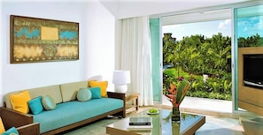 A modern living room with a sofa, a coffee table, a TV, and a view of greenery through a sliding glass door.