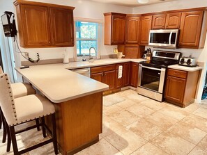 A kitchen with wooden cabinets, a stainless steel microwave, an oven, and a sink.