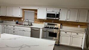 A modern kitchen with white cabinets, a stainless steel stove, and a microwave. - Cabin Retreat in Forest Lakes ... 2 hours from the Valley (Forest Lakes Estates)