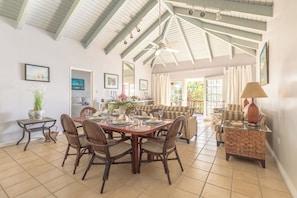 Un coin repas avec une table et des chaises en bois, un ventilateur de plafond et une vue sur lâextĂ©rieur.