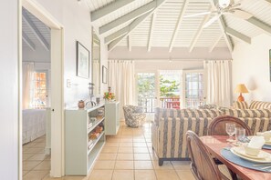 A spacious living area with a high ceiling, a sofa set, a dining table with chairs, and a bookshelf. - Oceanfront 3 Bedroom Signature Villa (Tortola)