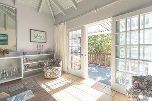 Ein geräumiges Zimmer mit großem Fenster, weißer Decke und Blick ins Freie.