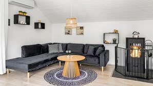 Una sala de estar moderna con un sofá seccional negro, una mesa de centro de madera y una chimenea negra.