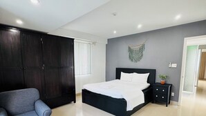 A modern bedroom with a bed, a sofa, a small table, and a wardrobe.