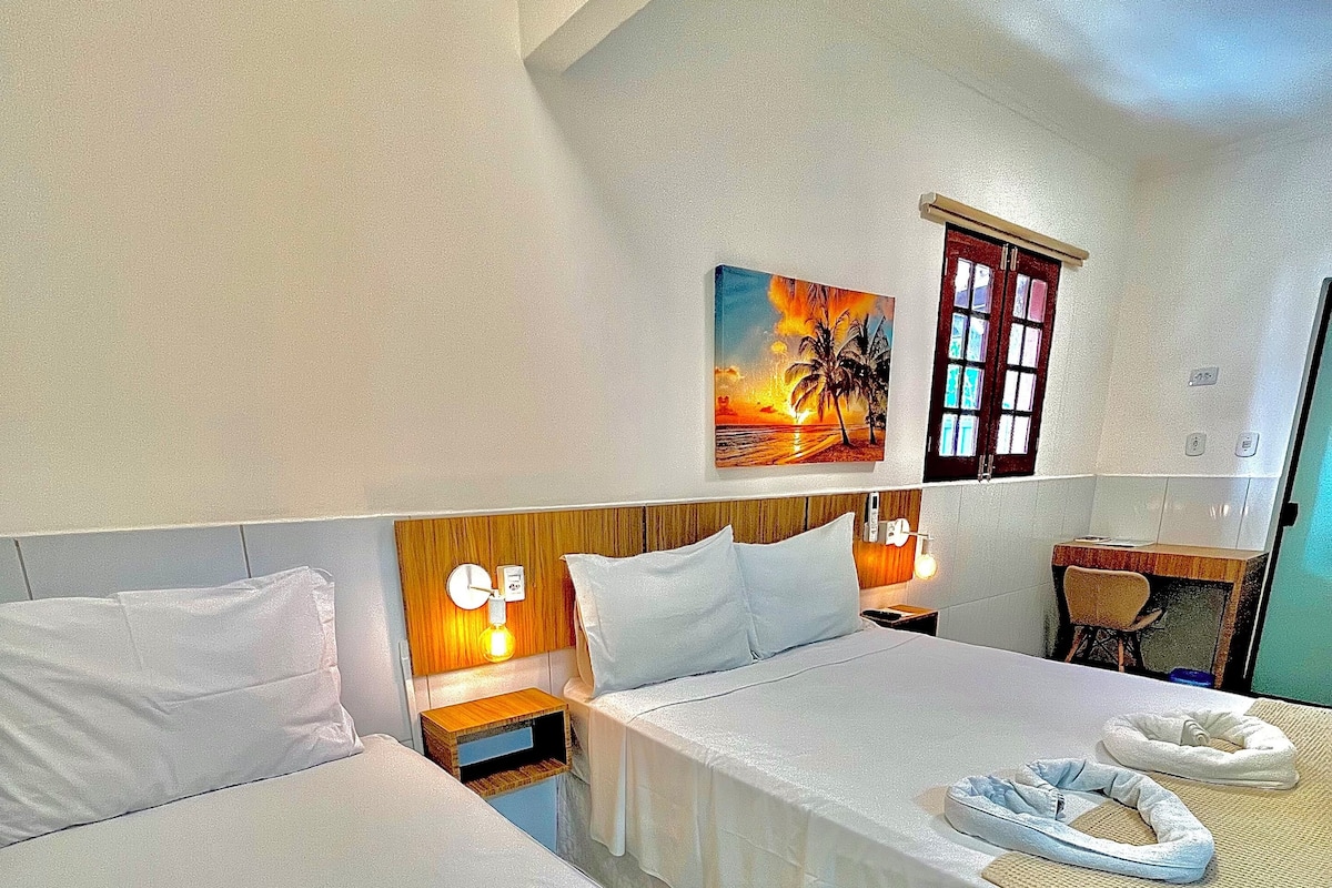 Habitación de hotel con dos camas, un escritorio, una silla, un cuadro y una ventana.