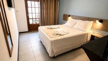 Habitación de hotel con cama, escritorio, silla, ventana con cortinas e iluminación en el techo.