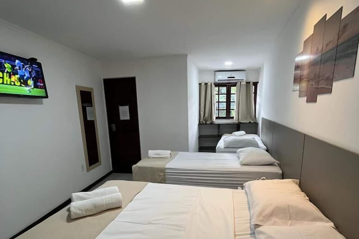 Habitación de hotel con dos camas, un televisor de pantalla plana, una ventana con cortinas y una obra de arte colgada en la pared.