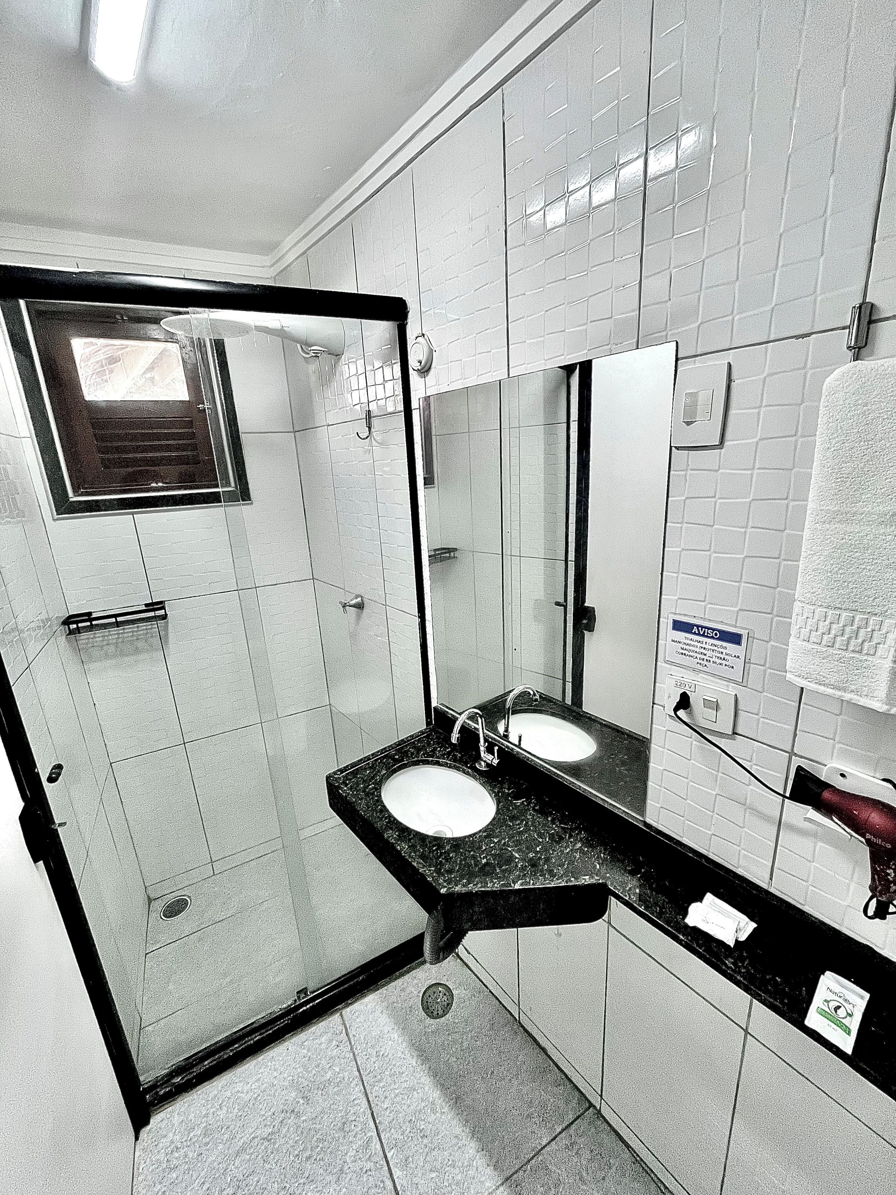 A bathroom with a glass shower enclosure, two sinks with mirrors, and a towel hanging on a rack.