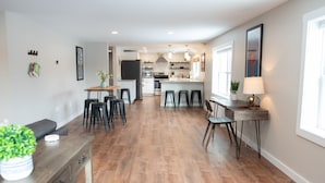 A modern kitchen with a central island, bar stools, and a dining area with a wooden table and chairs. - Spacious and Bright Downtown APT with River View (Ellsworth)