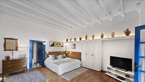 Une chambre à coucher comprenant un lit, une commode, un meuble pour la télévision et des vases décoratifs disposés sur des étagères.