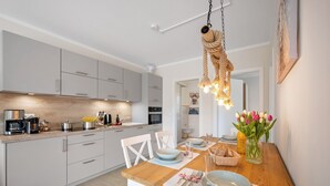 Une cuisine moderne avec des armoires blanches, un plan de travail en bois et un luminaire suspendu.