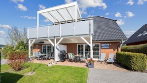 Un bâtiment à deux étages doté d’un patio couvert, d’un espace extérieur aménagé pour s’asseoir et d’une façade en briques.