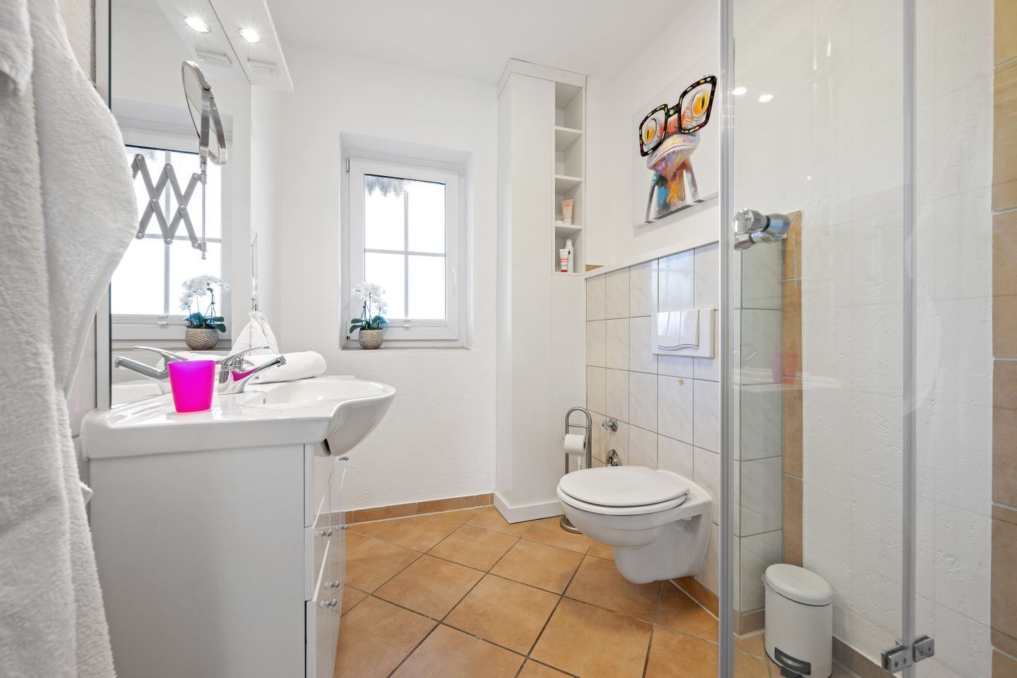 Un bany modern amb un lavabo blanc, un vàter i una zona de dutxa.