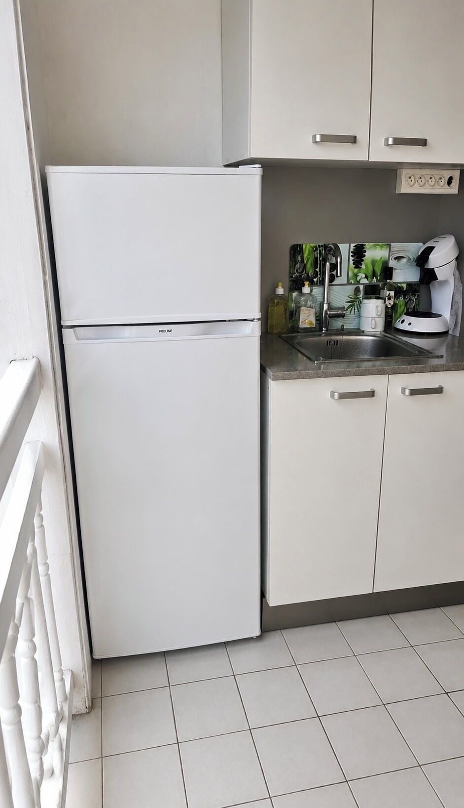 Una cocina con un refrigerador blanco, un lavamanos y armarios.