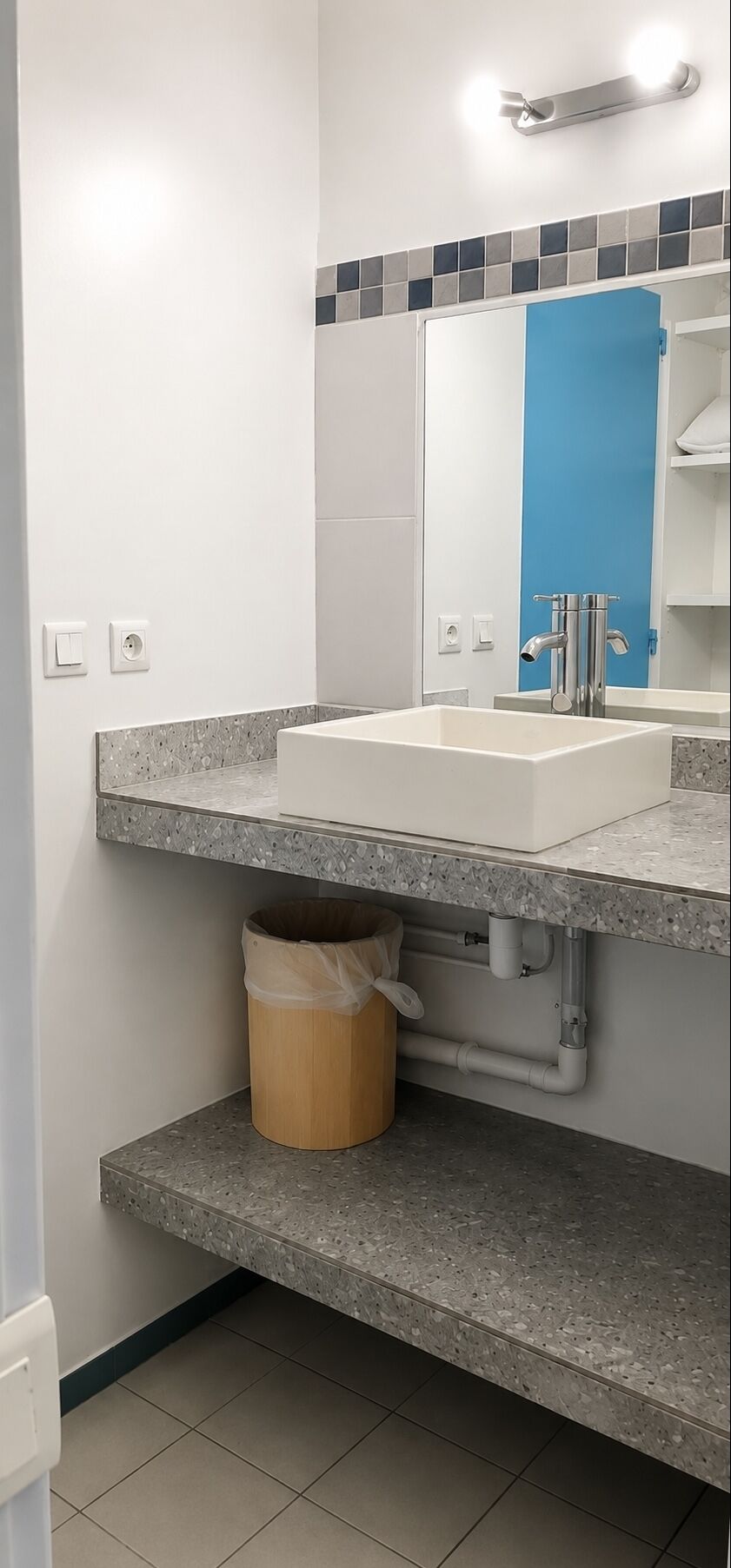 A bathroom with a white sink, a blue door, and a mirror above the sink.