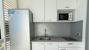 A compact kitchen with white cabinets, a built-in microwave, a stainless steel sink, and a refrigerator. - 3-person studio deck 15m2 facing Le Diamant (Le Diamant)