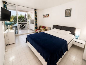 Une chambre Ă coucher comprenant un lit, une tĂ©lĂ©vision, une table de chevet, une lampe et une vue sur lâextĂ©rieur.