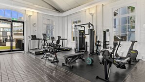 Ein modernes Fitnessstudio mit unterschiedlichen Trainingsgeräten, großen Fenstern und einem aufgeräumten, geräumigen Layout.