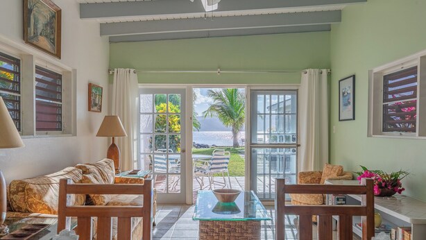 A room with a sofa, dining table, chairs, and a view of the ocean. - Oceanfront 2 Bedroom Premium Villa (Tortola)