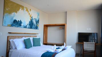 Una habitación de hotel con una cama grande, cabecera de madera, televisor y un cuadro en la pared.