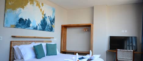 A hotel room with a large bed, a wooden headboard, a TV, and a painting on the wall.