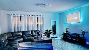 Una sala de estar con un sofá modular, una mesa de centro y un televisor de pantalla plana montado en la pared.