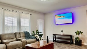 Una sala de estar moderna con un sofá de cuero, una mesa de centro de madera y un televisor de pantalla plana montado en la pared.